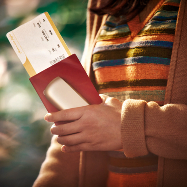 Chica con un pasaje de avión, un dispositivo IQOS y un pasaporte en la mano