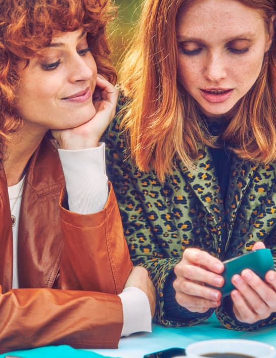 Dos mujeres mirando un dispositivo IQOS.
