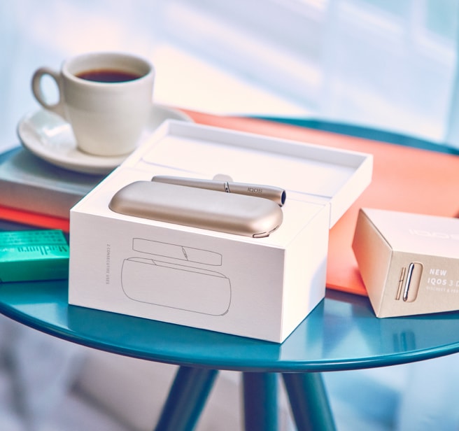 A package containing a gold IQOS device and holder.