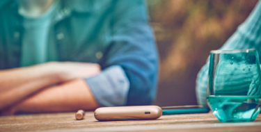 IQOS DUO sobre una mesa mientras dos personas hablan