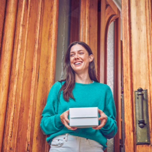 Chica sonriendo con una caja IQOS en sus manos