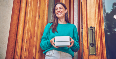 Chica sonriendo con una caja IQOS en sus manos
