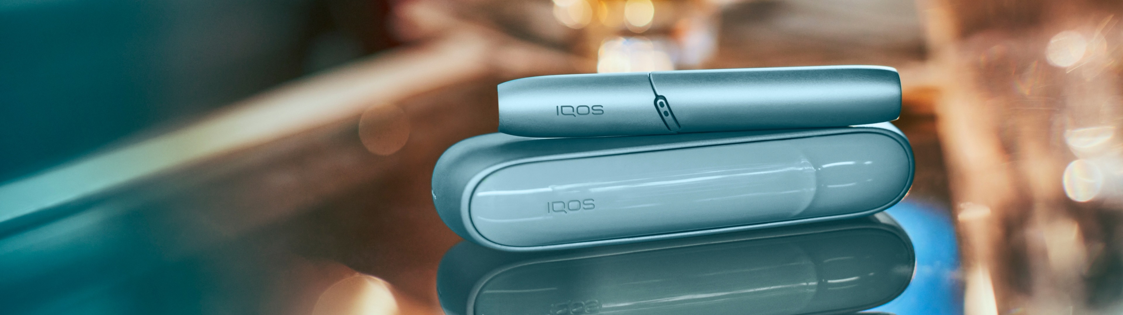 Dispositivo IQOS Original DUO en turquoise sobre mesa brillante.