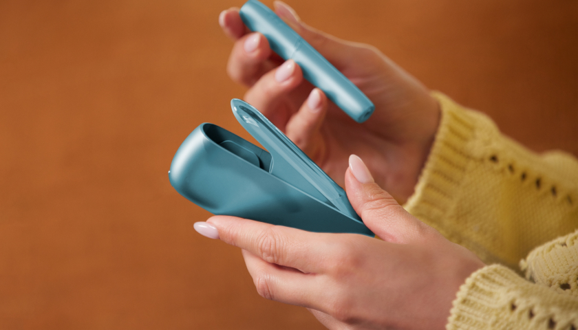 Manos sosteniendo un Holder y un Pocket charger de IQOS Originals Duo en color turquesa