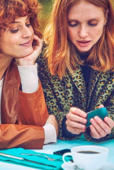 Dos mujeres mirando un dispositivo IQOS.