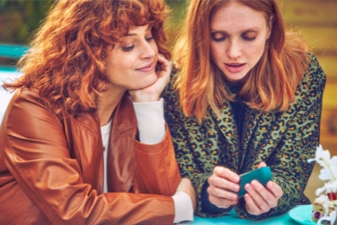 Dos mujeres mirando un dispositivo IQOS.