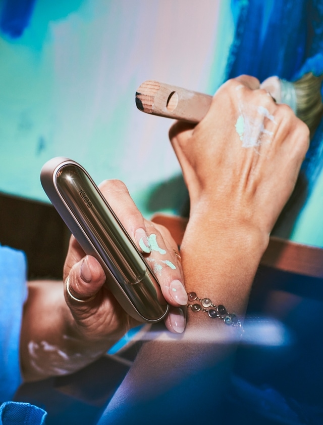 Una mujer sosteniendo un dispositivo IQOS. 