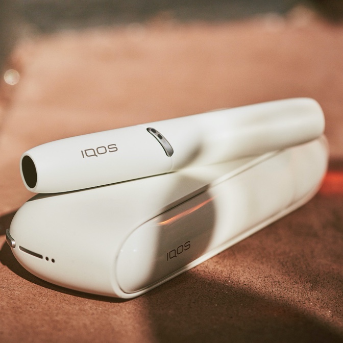 Dispositivo IQOS blanco sobre el cargador encima de una mesa