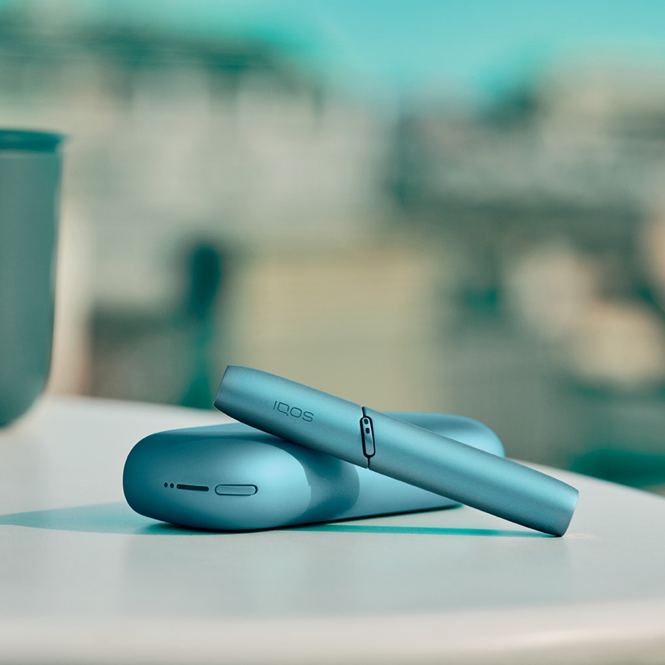 Holder y pocket charger de IQOS Originals Duo turquesa en la mesa. 