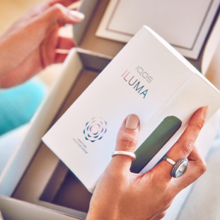 Una persona abre una caja que contiene un nuevo IQOS ILUMA.