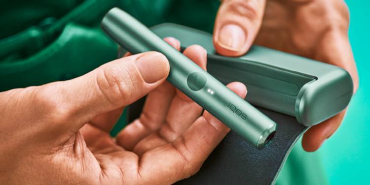 Un Holder IQOS ILUMA PRIME en las manos de una persona; las luces son visibles. 