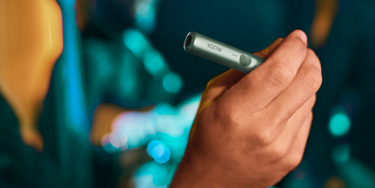 Un Holder IQOS ILUMA PRIME en las manos de una persona; .