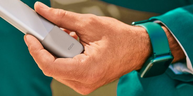 Mano sosteniendo un dispositivo IQOS ONE Pebble Beige.