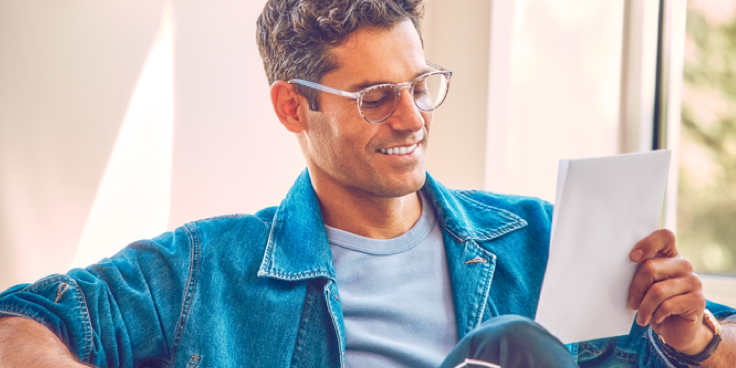Un hombre con gafas leyendo una hoja de garantía.