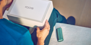 Una persona sostiene una caja sin abrir del dispositivo IQOS.